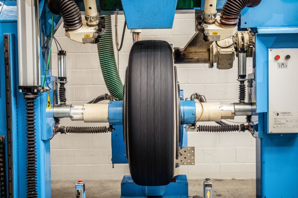 The AcuTread® Computerized Buffing machine buffs a commercial truck tire, providing a tolerance within 1/32″ in diameter.