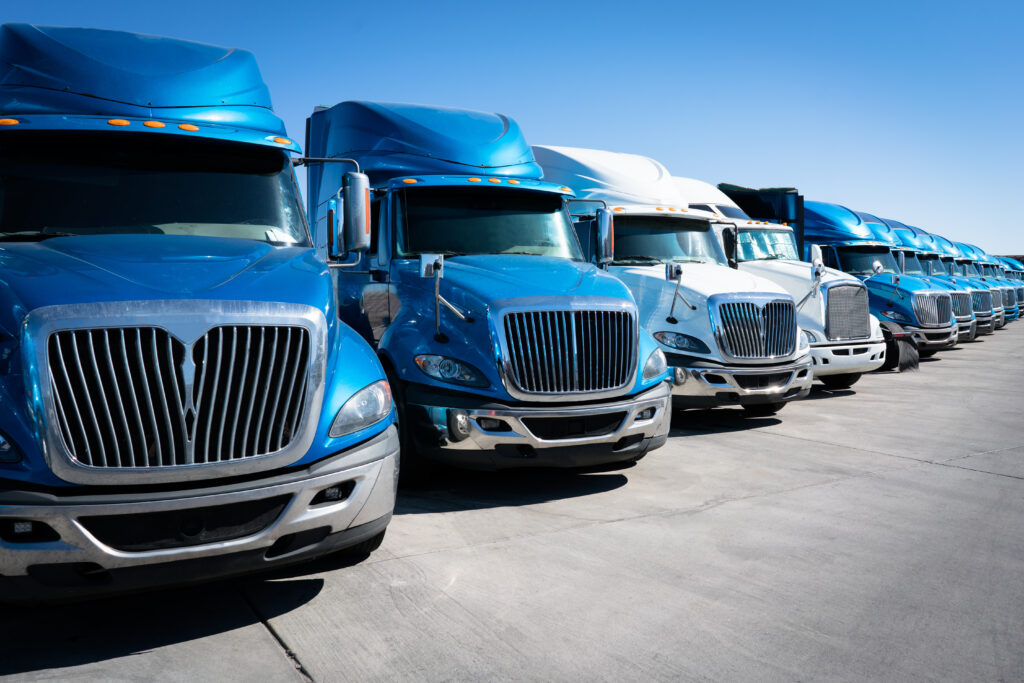 A fleet of blue and white semi-trucks using remanufactured tires are parked in a line