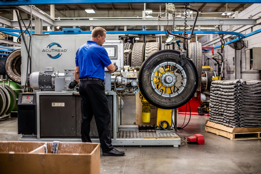 An AcuTread® technician applies a thin layer of high-tack, uncured cushion rubber to a premium tire casing.