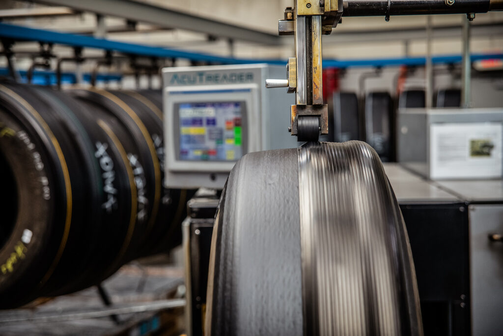 A digitally controlled extruder applies a continuous splice-free strip to the tire casing.